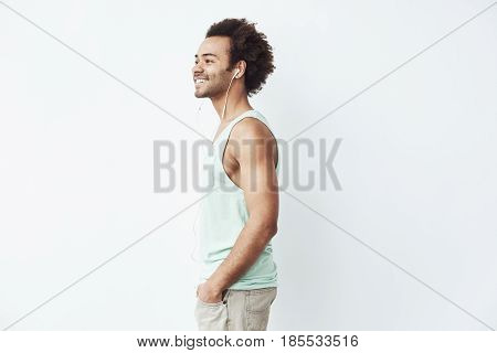 Young african man smiling listening to music in headphones over white background. Copy space.