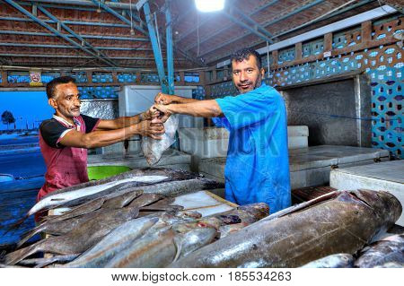 Bandar Abbas Hormozgan Province Iran - 15 april 2017: Iranian fishmonger passes assistant fresh flounder on the covered fish market.