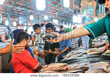 Bandar Abbas Hormozgan Province Iran - 16 april 2017: The seller of the fish market gives the assistant a mobile terminal for reading credit cards.