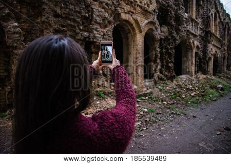 Young woman tourist photographing old ruins Tarakanovskiy fort Ukraine