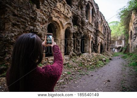 Young woman tourist photographing old ruins Tarakanovskiy fort Ukraine