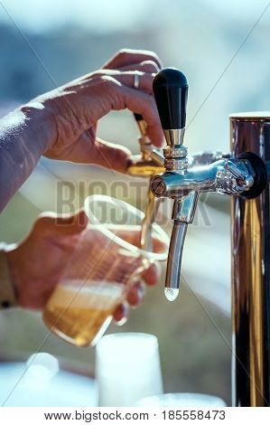 close-up of barman hand at beer tap pouring a draught lager beer