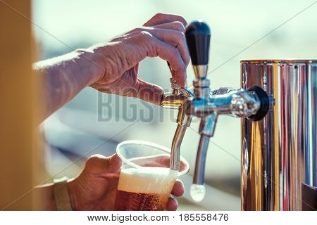 close-up of barman hand at beer tap pouring a draught lager beer