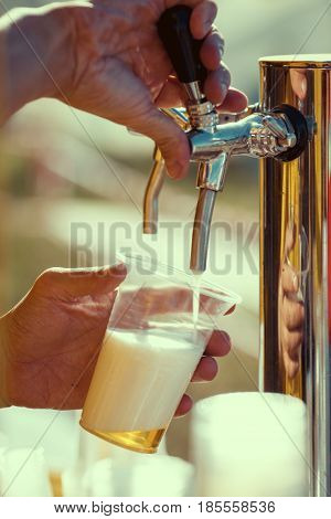 close-up of barman hand at beer tap pouring a draught lager beer