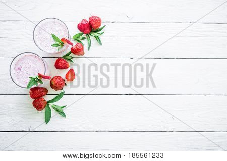 Blueberry smoothie with strawberry on white wood background. Flat lay. Top view. Fresh milkshake