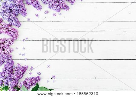 Floral pattern made of blue lilac branches and petals on white wooden background. Flat lay, top view. Floral purple frame