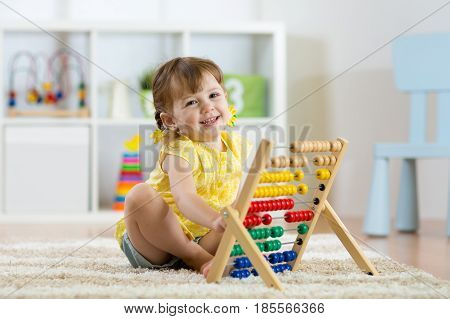 smiling kid girl playing with counter toy in nursery room