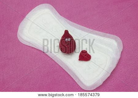 Hygiene conception photo. Menstruation sanitary soft pad for woman hygiene protection crochet red heart and crochet funny blood drop. Woman critical days gynecological menstruation cycle