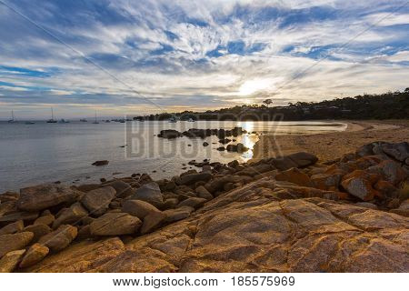 Evening sunset on Freycinet national park beach. Last sunlight reflecting on Coles Bay in East coast of Tasmania, Australia