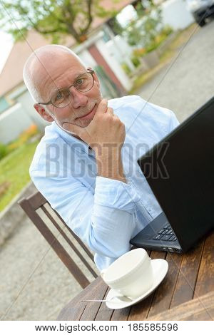 A senior man using a laptop outside