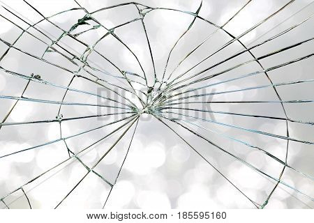 Broken window glass on a grayish bright bokeh background