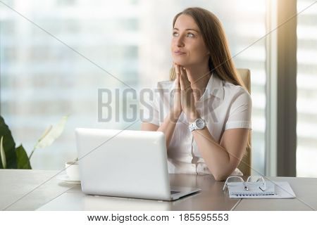Dreamy businesswoman anticipates dearest wish comes true. Happy young woman with exited facial expression imagines her great success while sitting at office. Female seeing herself in incredible future