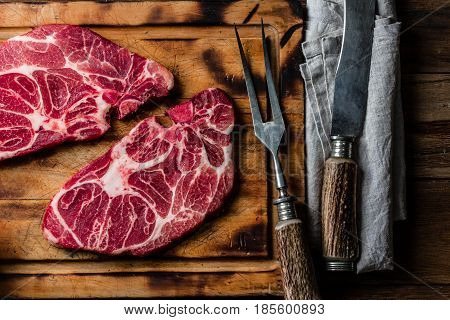 Meat. Two raw beef marbled meat steak on wooden cutting board, meat carving set, rustic background. Top view