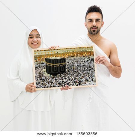 Muslim man posing as ready for Hajj visiting Kaaba in Mecca holding banner frame of The Holy Place