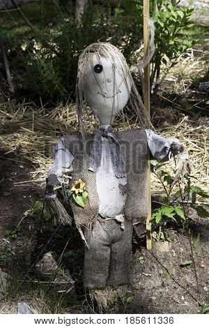Close up vertical of a whimsical scarecrow in a dried out garden in Notre Dame de Ile Perrot, Quebec on a sunny day in June.