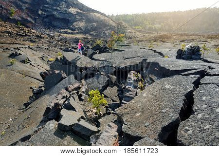 Young Female Tourist Exploring Surface Of The Kilauea Iki Volcano Crater With Crumbling Lava Rock In