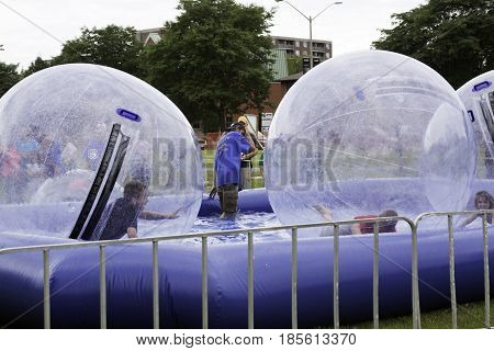 Cornwall, Quebec - July 26, 2014 - Wide view of children playing inside large plastic bubbles in a pool at the Ribfest in Cornwall, Ontario on a sunny afternoon in July.