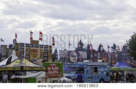 Cornwall, Quebec - July 26, 2014 - Wide view of the colorful billboard signs vendors tents and people at the Ribfest in Cornwall, Ontario on a sunny afternoon in July.