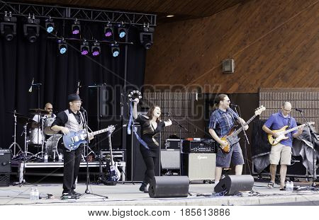 Cornwall, Quebec - July 26, 2014 -- Wide view of a band playing pop music at the Ribfest in Cornwall, Ontario on a sunny afternoon in July.