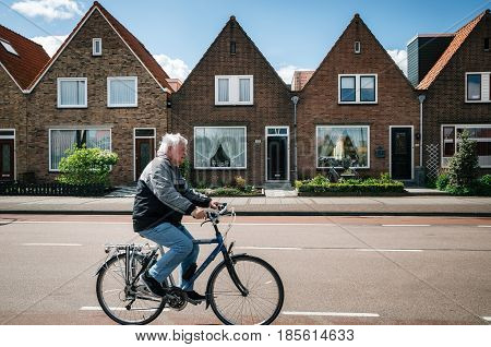 Volendam Netherlands - 26 April 2017: Resident of the village of Volendam by bike in front of the typical traditional houses of a Dutch fishing village Netherlands.