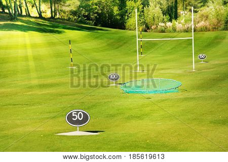 Driving range at golf course with yard signs, flagsticks and balls for practicing swing