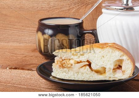 Fresh homemade apple pie and tea with milk on a wooden background