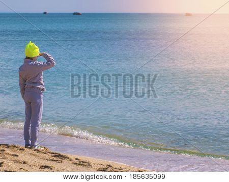 The child in sports clothes looking into the sea