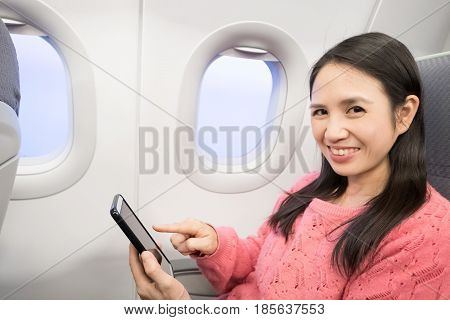 Middle aged woman smie and use phone in the airplane