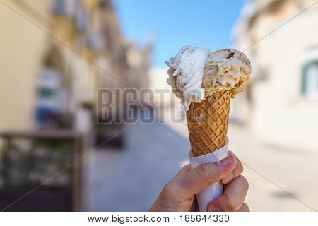 Close up focus of female hand holding delicious ice cream gelato in summer Italy.