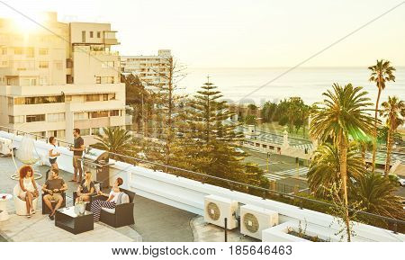 Good looking group of happy, successful young adults having a barbaque on a rooftop in summer.