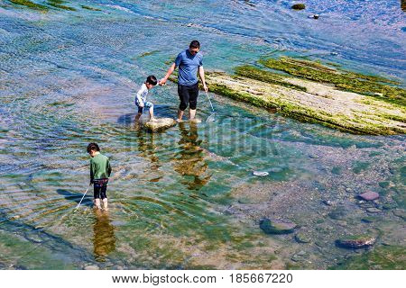 KEELUNG TAIWAN - APRIL 04: Taiwanese family fishing in clean shallow water in the seaside area of Keelung on April 04 2017 in Keelung