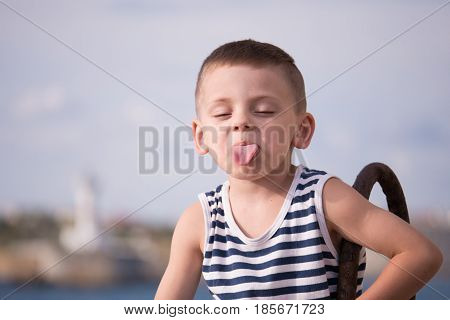 Funny boy in sailor stripes vest showing tongue closing his eyes