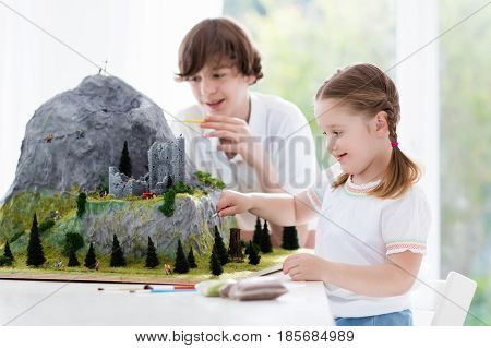 Children work on model building school project. Kids build miniature scale model mountain for geography class. Extracurricular activities and hobby club. Art and crafts for teenager and preschool.