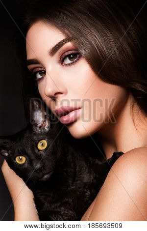 portrait of the beautiful young woman with cat on the black background