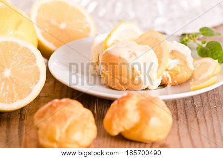 Lemon Profiteroles with custard cream on white dish.
