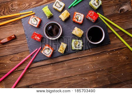 Sushi Set rolls with soy sauce served on gray stone slate on wooden background