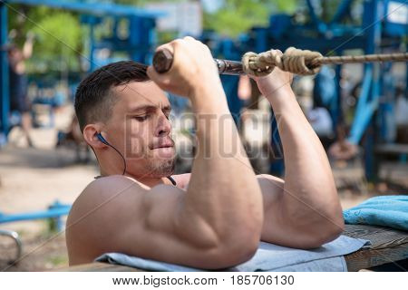 A hard-working guy is doing sports exercises in the park