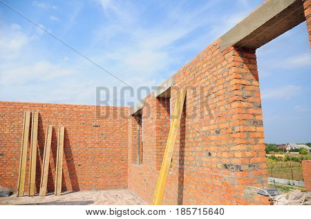 Unfinished house. House construction concept. Interior of a unfinished red brick house under construction. Closeup on windows hole construction with concrete lintel.