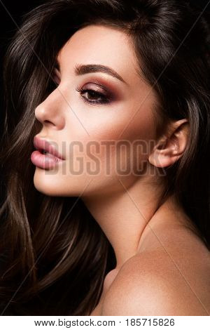 Glamour portrait of beautiful girl model with makeup and romantic wavy hairstyle. Fashion shiny highlighter on skin, sexy gloss lips make-up and dark eyebrows.