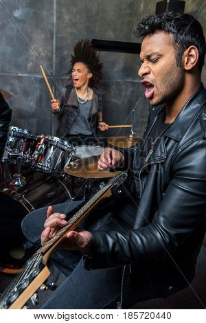 side view of man playing guitar with woman playing drums hard rock music concept