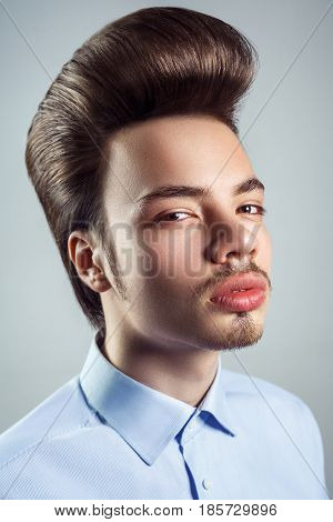 Portrait of young man with retro classic pompadour hairstyle. studio shot. looking at camera.