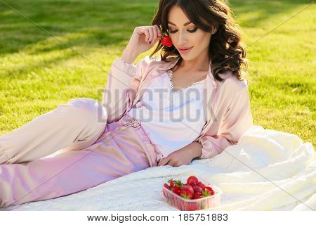 Beautiful Girl With Dark Hair Relaxing At Summer Picknic, Eating Strawberries