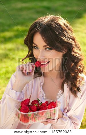 Beautiful Girl With Dark Hair Relaxing At Summer Picknic, Eating Strawberries