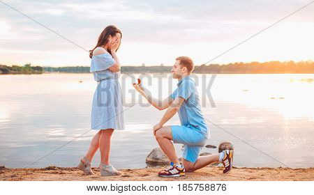 Marriage proposal on sunset . young man makes a proposal of betrothal to his girlfriend on the beach