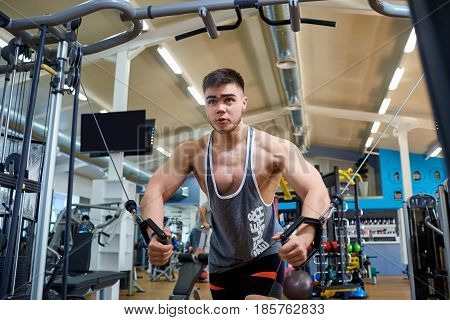 A man athlete does exercises on  simulator in the gym.