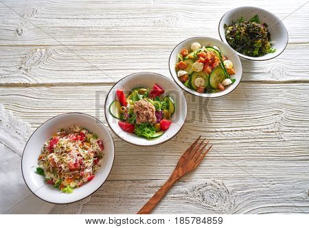 four salad mix bowls healthy food on white wood table