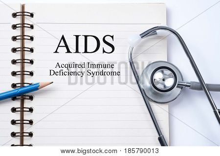 Stethoscope on notebook and pencil with AIDS (Acquired Immune Deficiency Syndrome) words as medical concept.