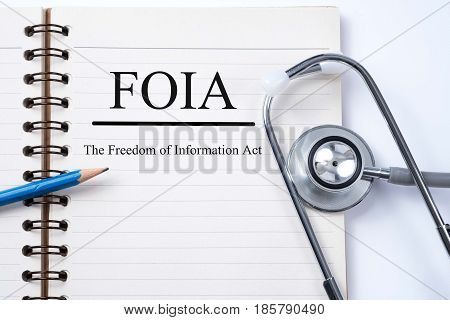 Stethoscope on notebook and pencil with FOIA (The Freedom of Information Act) words as medical concept.