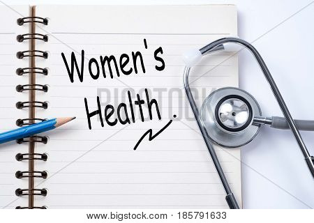 Stethoscope on notebook and pencil with women's health words as medical concept
