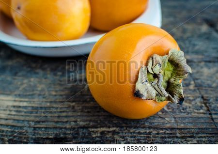 Ripe delicious fresh persimmon kaki fruit on old wooden table with place for text. Copy space.